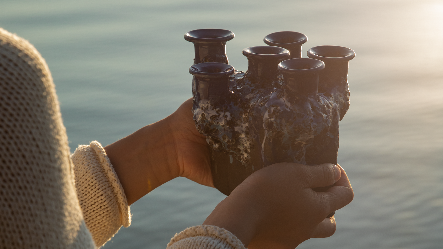 Hands holding a Pentik Kaamoskivi candelabra with calm lake on the background.